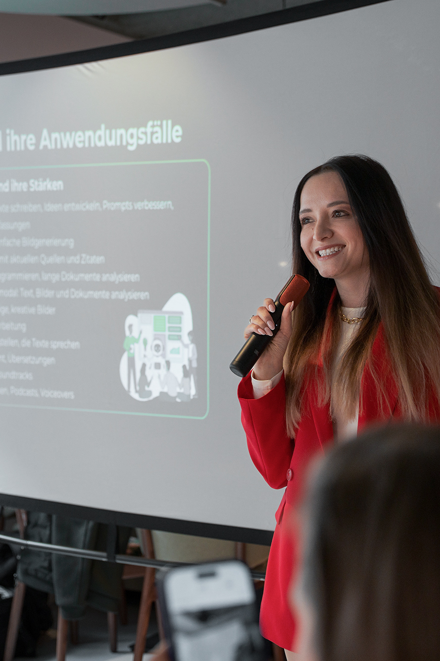 Eventfotografie Konferenz Nürnberg: Speakerin im roten Anzug erklärt KI-Tools, Anton Gil Fotografie.
