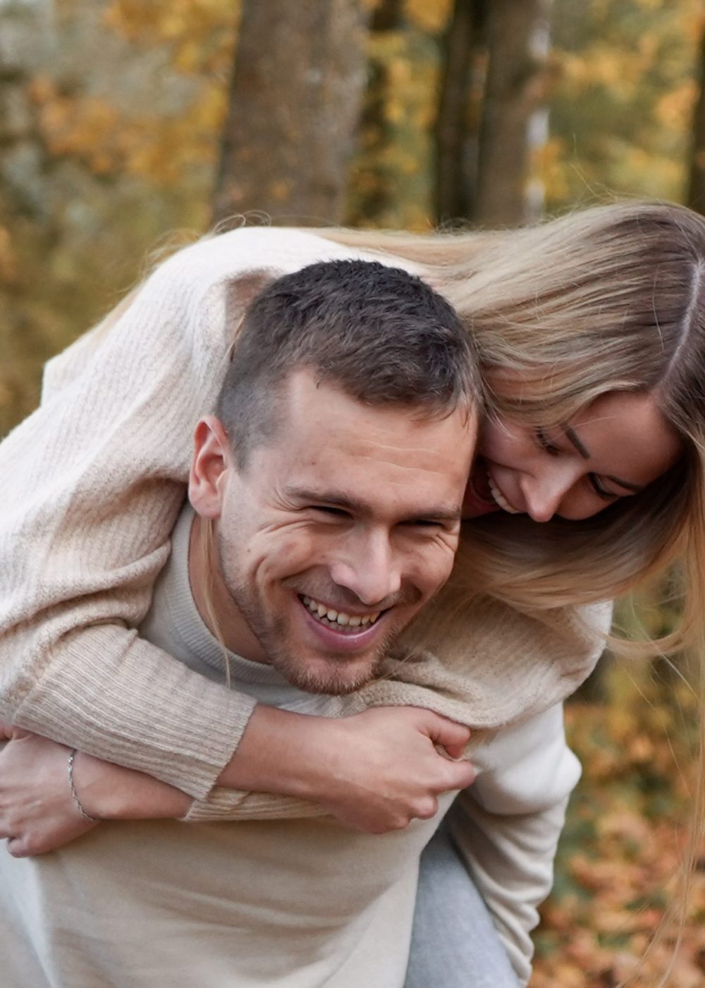 Pärchenfotografie Ingolstadt: Freundin sitzt auf dem Rücken des Partners im Herbstwald, ausgelassene Stimmung, Anton Gil Fotografie.